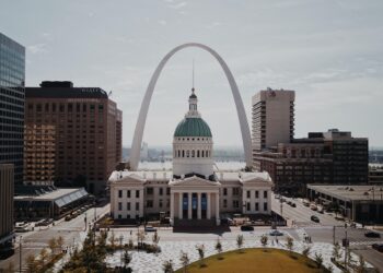 white and green dome cathedral in between high-rise buildings during daytime