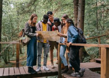 People Standing on a Wooden Bridge while Reading a Map