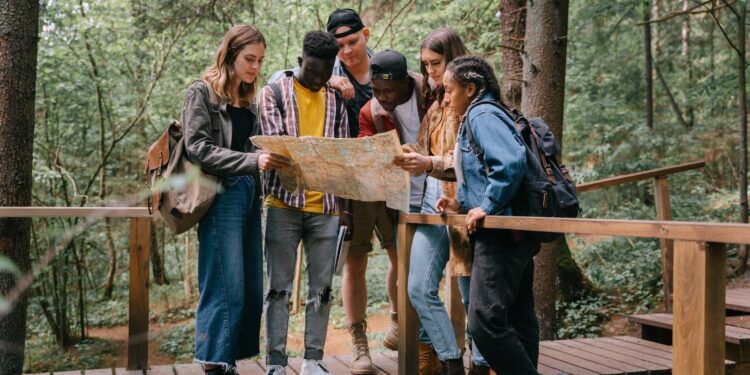 People Standing on a Wooden Bridge while Reading a Map
