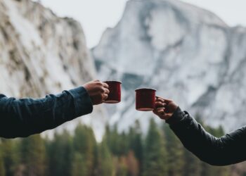 two person holding red mugs