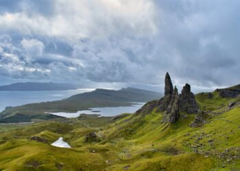 green grass field and mountain under white clouds during daytime