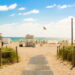 gray pathway leading to parasol, lifeguard house, and sea a daytime