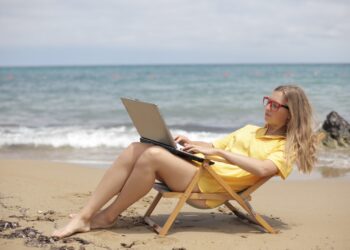 Woman in Yellow Shirt Sitting on Brown Wooden Folding Chair on Beach