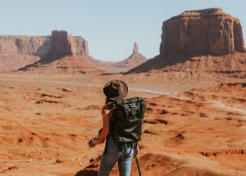 woman with black backpack standing on brown dessert