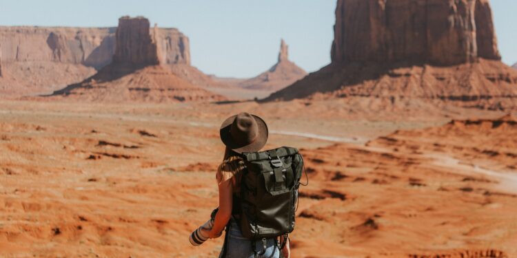 woman with black backpack standing on brown dessert