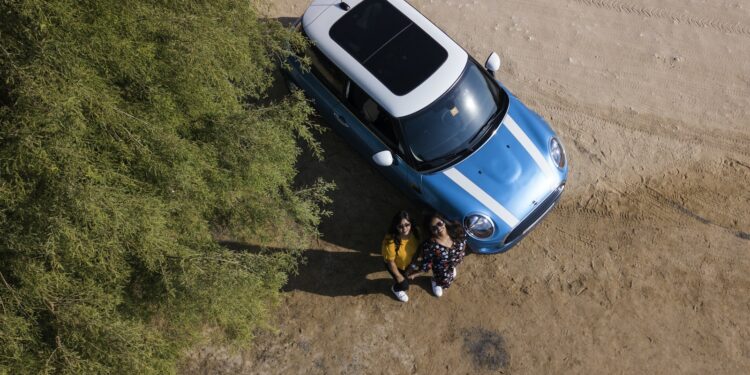 Two Woman Standing Beside Blue Mini Cooper