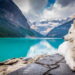 A white dog sitting on a rock formation near a large mountain pond.