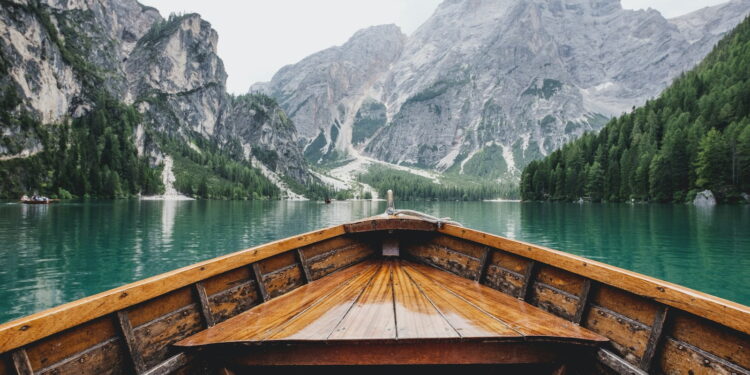brown wooden boat moving towards the mountain