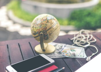 gray desk glove above U.S dollar beside iPhone and white airpods