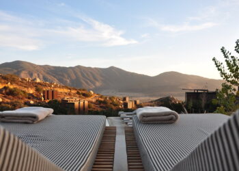 a luxury view with sunloungers fronting buildings near mountain