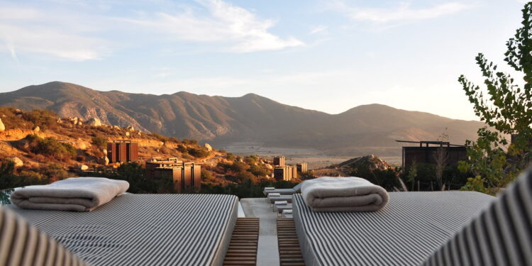a luxury view with sunloungers fronting buildings near mountain