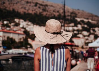 woman wearing gray and white striped sleeveless top and brown sun hat at daytime