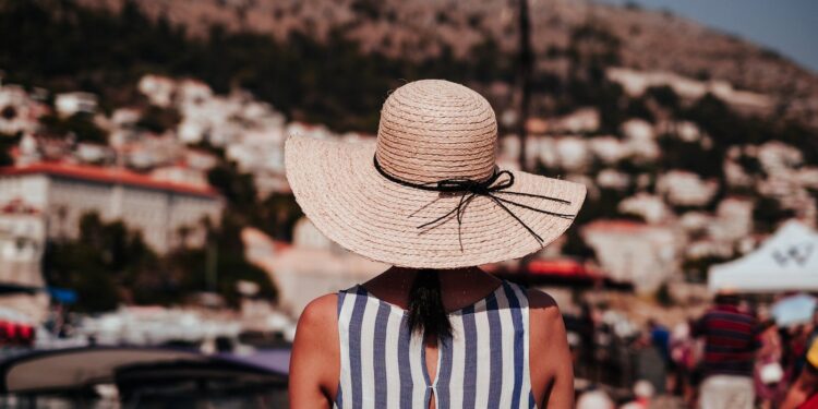 woman wearing gray and white striped sleeveless top and brown sun hat at daytime