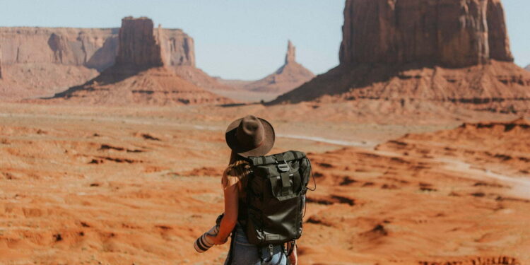 woman with black backpack standing on brown dessert