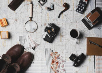 camera, pair of brown shoes, white ceramic mug, grey and black pen, brown smoking pipe